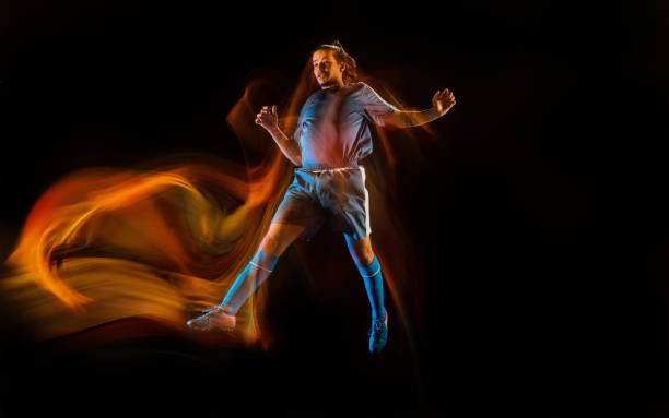 istock Football or soccer player on black background in mixed light, fire shadows 1273297838