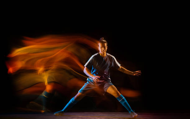 istock Football or soccer player on black background in mixed light, fire shadows 1273297843