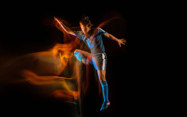 Football or soccer player on black background in mixed light, fire shadows