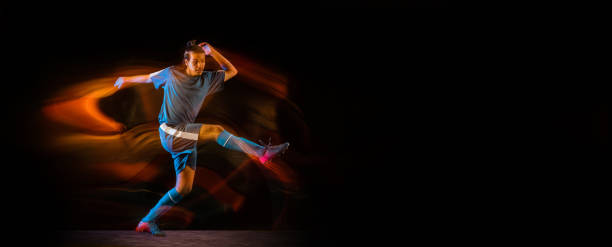 istock Football or soccer player on black background in mixed light, fire shadows 1273297846