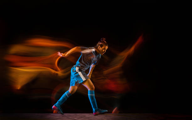 istock Football or soccer player on black background in mixed light, fire shadows 1273297855