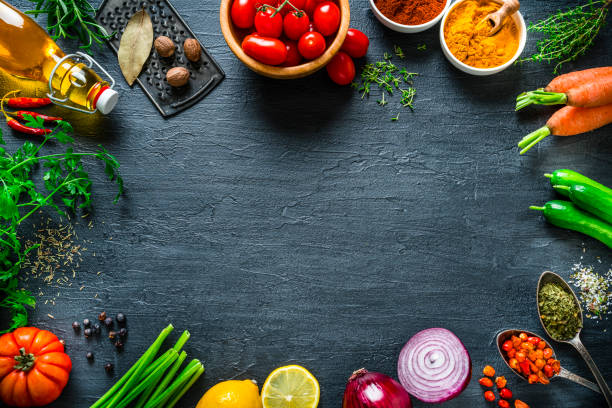 istock Multi colored vegetables and spices frame on black slate background. Overhead view 1273297928