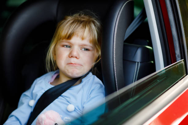 smutna zdenerwowana dziewczynka siedząca w samochodzie w korku podczas wyjazdu na letnie wakacje z rodzicami. zmęczone, wyczerpane dziecko nie jest zadowolone z długiej podróży. płacz dziecka. - traffic jam traffic germany car zdjęcia i obrazy z banku zdjęć