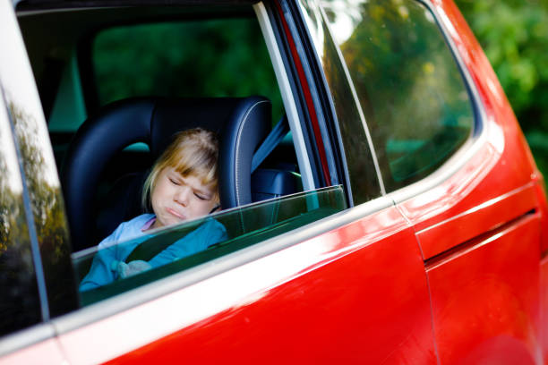 smutna zdenerwowana dziewczynka siedząca w samochodzie w korku podczas wyjazdu na letnie wakacje z rodzicami. zmęczone, wyczerpane dziecko nie jest zadowolone z długiej podróży. płacz dziecka. - traffic jam traffic germany car zdjęcia i obrazy z banku zdjęć