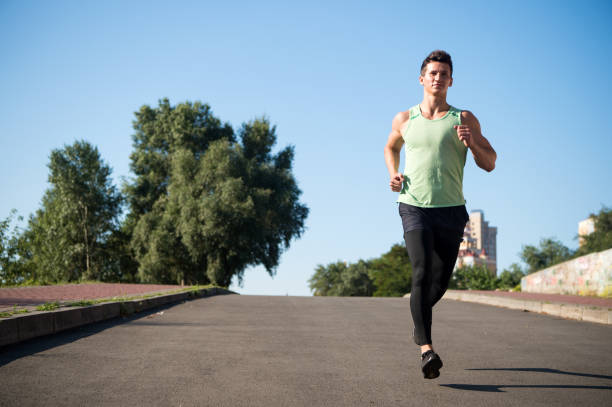 istock Man running on asphalt road on sunny summer day 1273302754