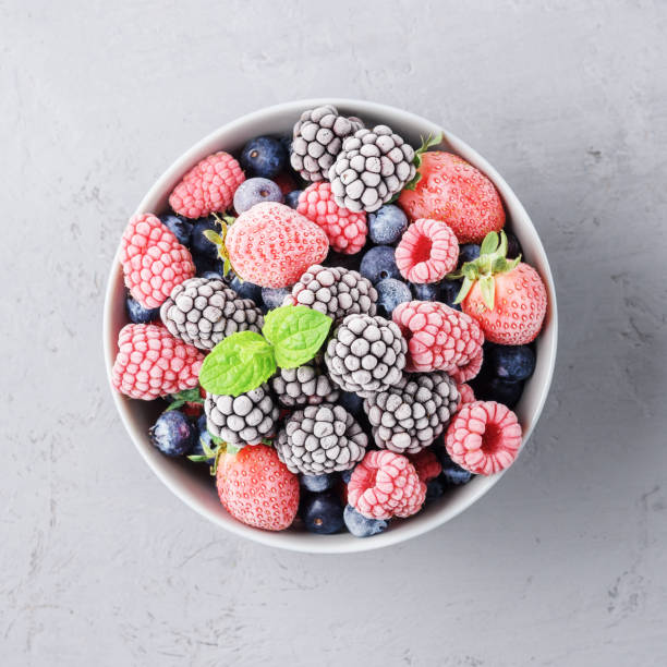 istock Frozen berries in a grey bowl on a grey concrete background. 1273303783