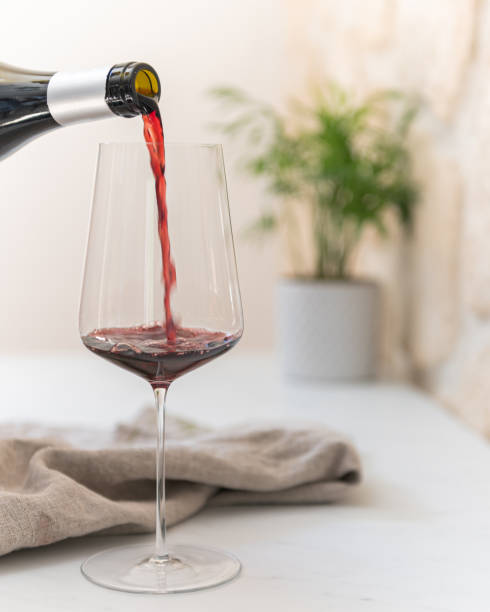 Pouring red wine on a marble counter clean surface, linen and plant in the background out of focus wine bar counter stock pictures, royalty-free photos & images