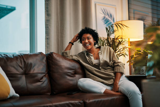 Time to myself is just what I needed Shot of a beautiful young woman sitting on the sofa at home leather couch stock pictures, royalty-free photos & images