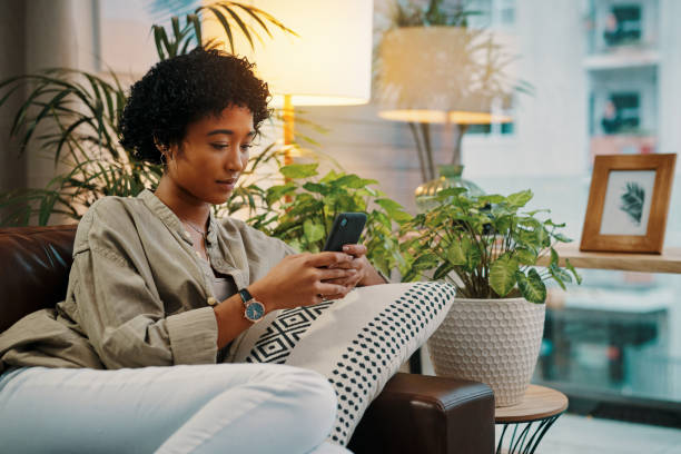 I started reading this e-book and I just can't put it down Shot of a beautiful young woman using her cellphone while sitting at home put down stock pictures, royalty-free photos & images