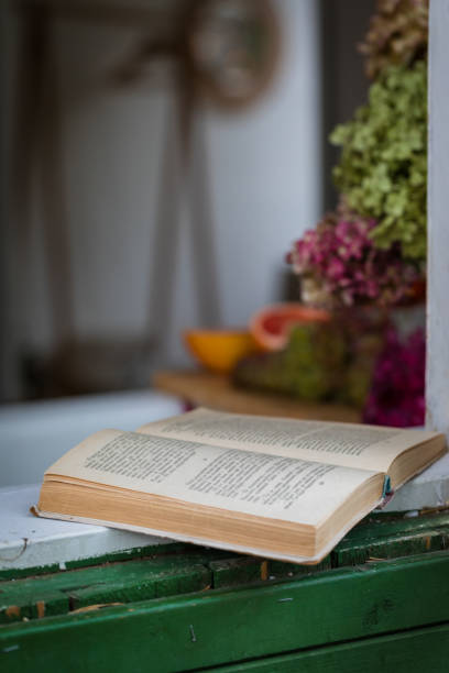 istock Old open book on windowsill or desk with daylight, defocused background 1273307913