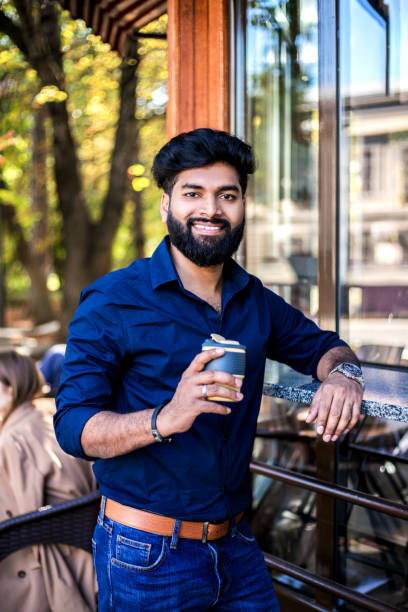 istock Young Indian man drinking coffee from reusable cup outdoors. 1273311703