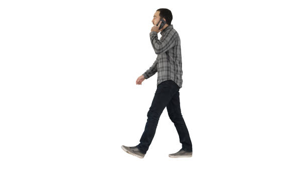 Young bearded man walking and talking on the mobile phone on whi