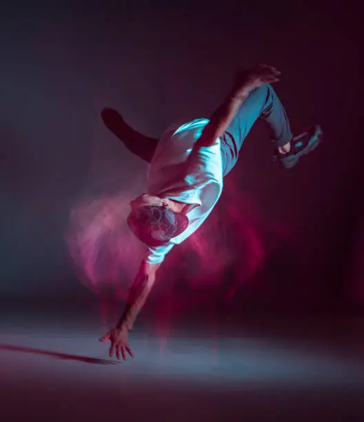 Cool young guy breakdancer dancing in neon light. Dance school poster. Long exposure shot. High quality photo