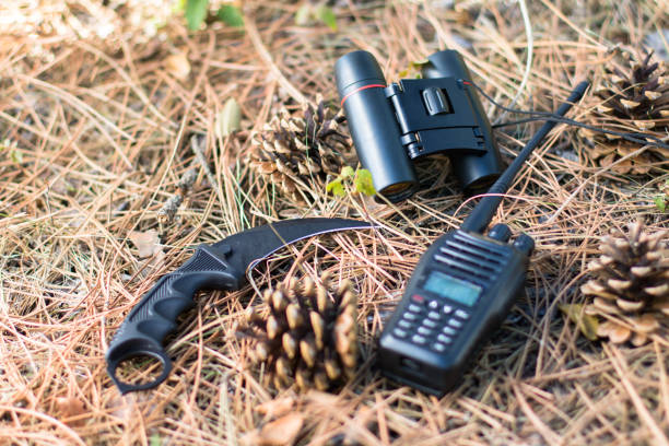 istock radio set, karambit knife and binoculars between fir cones on the ground in the forest 1273315436
