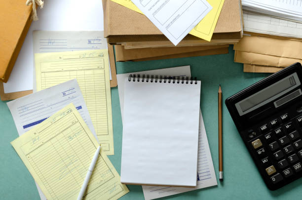 istock Top view of working process in the accountant office.Pile of bills, documents, notebook, calculator on the blue desk 1273318535