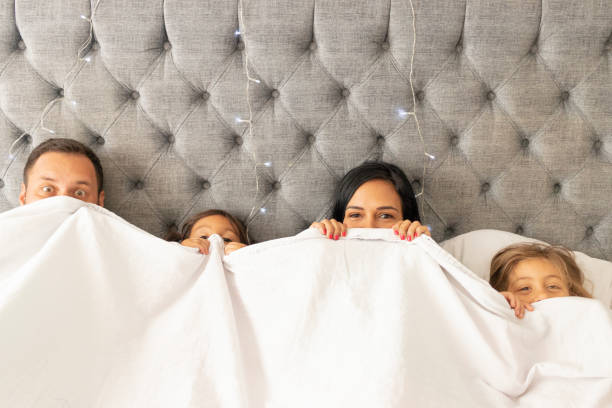 istock Cute family watching from her bed under the sheets 1273318622