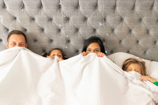 istock Cute family watching from her bed under the sheets 1273318627