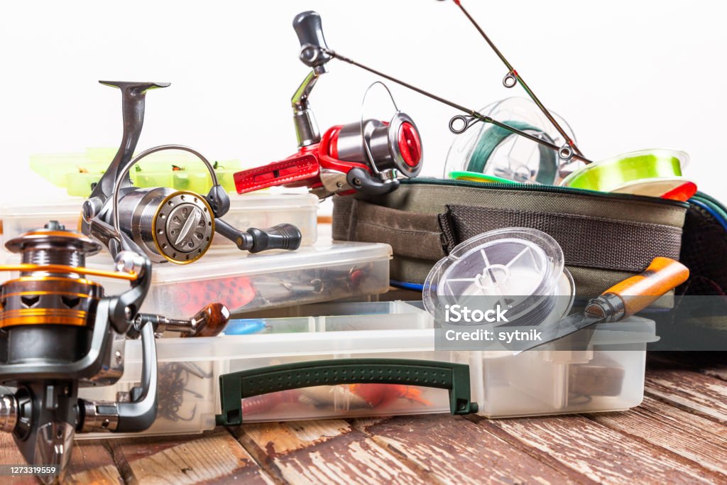 Different fishing tacles with rod and reels on wooden brown background. Mockap for advertisment and publishing. Fishing Tackle Stock Photo