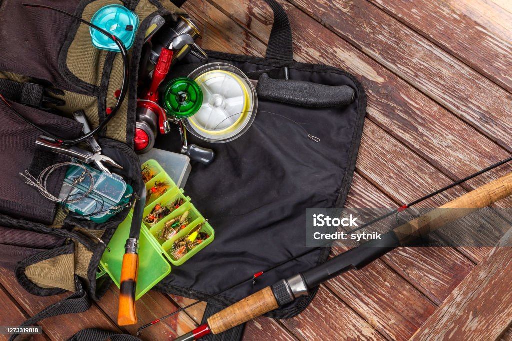 Different fishing tacles with rod and reels on wooden brown background. Mockap for advertisment and publishing. Box - Container Stock Photo