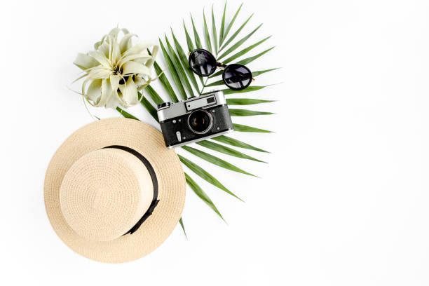 istock Flat lay traveler accessories on white background with retro camera, straw hat, sunglasses, and tropical palm leaf. Travel concept background 1273322870