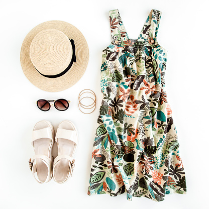 Mujer viaje de ropa de verano, collage sobre fondo blanco. Vestido de sol, sombrero de paja, gafas de sol. Vista superior, plana photo