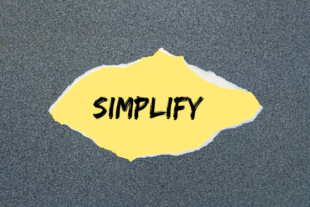 Simplify - written on torn yellow paper. stock photo