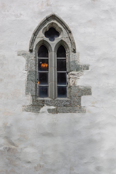istock Old stained glass window on white stone wall of medieval stone 1273325150