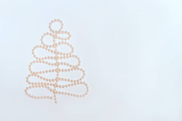 Pearl beads in Christmas tree shape on white background. Flat lay composition for Christmas, New Year. Free copy space for text.