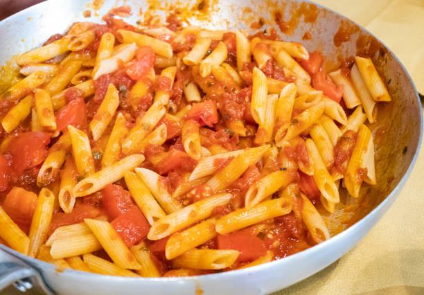 Italian pasta with garlic and oil and diced tomato, pennette rigate pasta, Italian recipe in the pot stock photo
