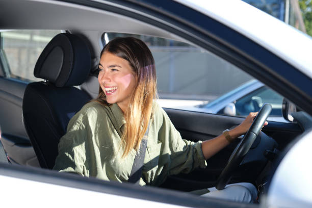 istock Young woman looking back in her car and laughing 1273328611