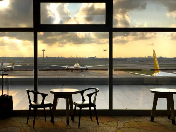 The concrete terminal of an airport with stationary planes on it, photographed through the window of Singapore airport.