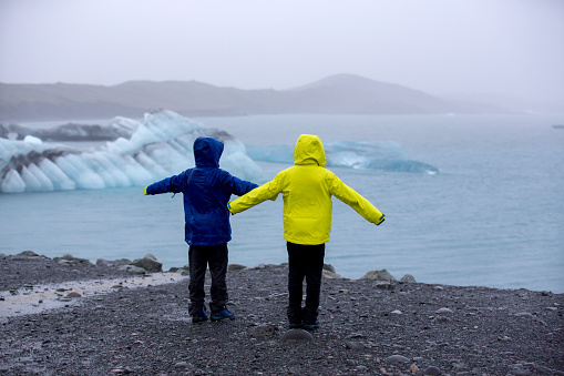 Child, taking picture at early evening on a rainy day at picturesque iceberg lagoon Jokursarlon in Iceland