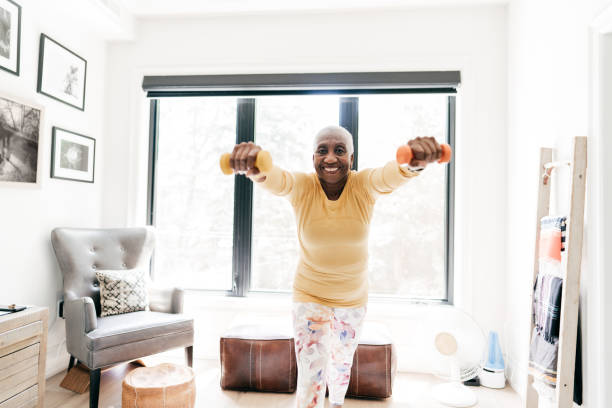 istock Senior women exercising with  dumbbells at home 1273330573