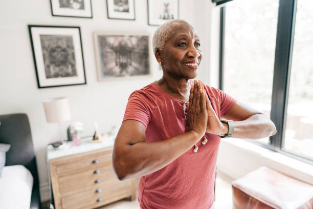 mujeres mayores cuidando de su bienestar, está haciendo ejercicio en casa en ropa deportiva - stretching yoga zen like beauty fotografías e imágenes de stock