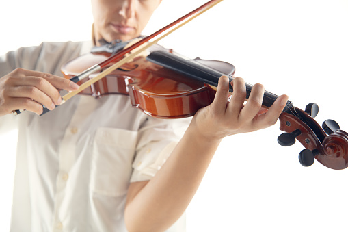 Portrait of aged 16-17 years old with brown hair caucasian male violinist standing in front of white background wearing pants who is happy and holding violin