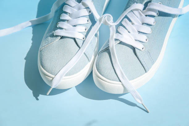 istock Blue sneakers with white laces on a light blue background. 1273333616