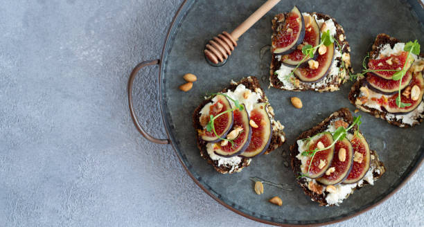 istock Sandwiches with fresh figs, cream cheese, nuts and honey on tray top view 1273334617
