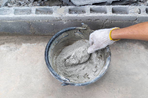 istock Mixing mortar by hand (wearing gloves) and trowel. 1273336172