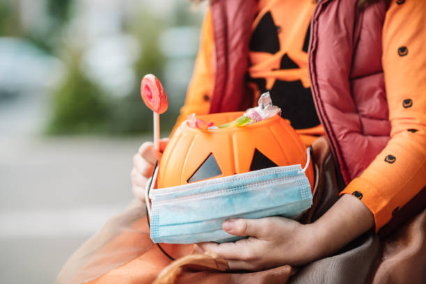 秋のハロウィーンでお菓子と保護フェイスマスクを持つ子供のバスケット - vegies vegetable basket residential structure ストックフォトと画像