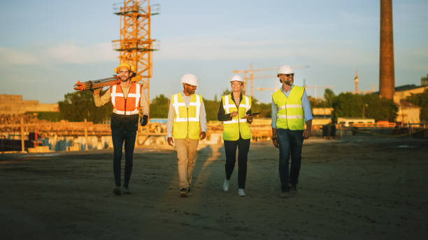 istock Diverse Team of Specialists Taking a Walk Through Construction Site. Real Estate Building Project with Senior Civil Engineer, Architect, Business Adviser and General Worker Discussing Casual Topics. 1273337039