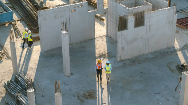 istock Aerial Shot of a New Constructions Development Site with Diverse team of Engineers and Architects Discussing Real Estate Projects. Heavy Machinery and Construction Workers are Working in the Area. 1273337041