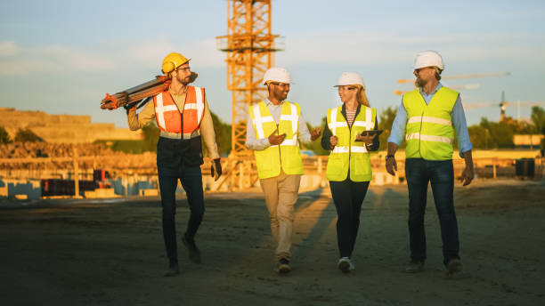 istock Diverse Team of Specialists Taking a Walk Through Construction Site. Real Estate Building Project with Senior Civil Engineer, Architect, Business Adviser and General Worker Discussing Casual Topics. 1273337103