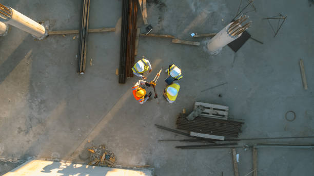 istock Aerial Top Down Shot of a Constructions Site with Diverse Team of Engineers and Worker with Theodolite Working. Heavy Machinery and Construction Workers in Hard Hats in the Area. 1273337620
