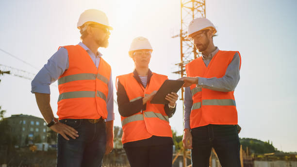 istock Team of Specialists Use Tablet Computer on Construction Site. Real Estate Building Project with Civil Engineer, Architect, Business Investor Discussing Planning and Development Details. Sun Flare. 1273337695