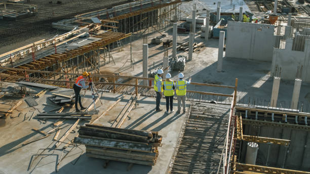 istock Aerial Shot of a New Constructions Development Site with Diverse team of Engineers and Architects Discussing Real Estate Projects. Heavy Machinery and Construction Workers are Working in the Area. 1273337701