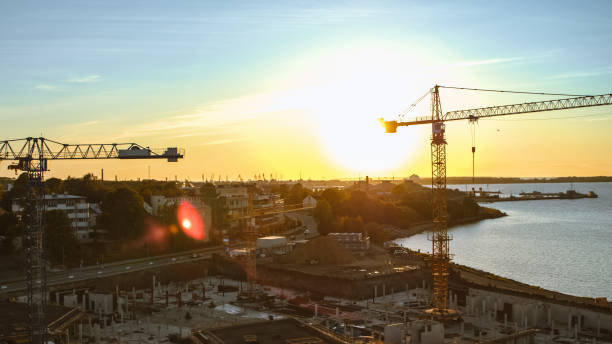 istock Aerial Shot of a New Constructions Development Site with High Tower Cranes Building Real Estate. Heavy Machinery and Construction Workers are Employed. Blue Sea and City Houses in the Background. 1273337713