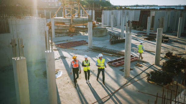 istock Diverse Team of Specialists Taking a Walk Through Construction Site. Real Estate Building Project with Senior Civil Engineer, Architect, General Worker Discussing Planning and Development Details. 1273337778