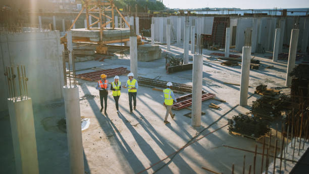 istock Diverse Team of Specialists Taking a Walk Through Construction Site. Real Estate Building Project with Senior Civil Engineer, Architect, General Worker Discussing Planning and Development Details. 1273337834