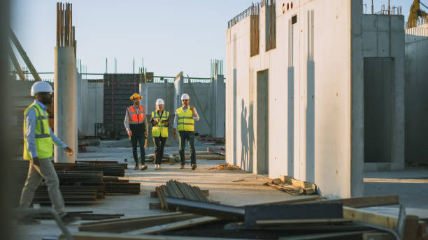 Diverse Team of Specialists Taking a Walk Through Construction Site. Real Estate Building Project with Senior Civil Engineer, Architect, General Worker Discussing Planning and Development Details.