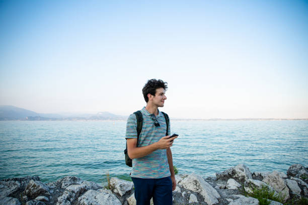 istock young man using phone in Sirmione enjoying sunset，Lombardy, Italy 1273338617